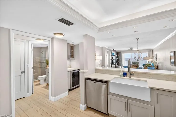 Kitchen with dishwasher, light stone countertops, glass insert cabinets, wood tiled floors, and ornamental molding