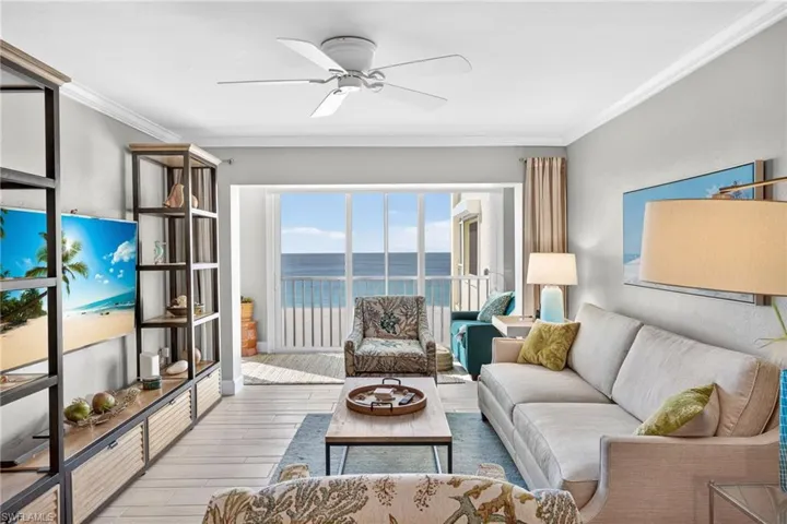 Living room featuring a water view, ornamental molding, ceiling fan, and wood finished floors