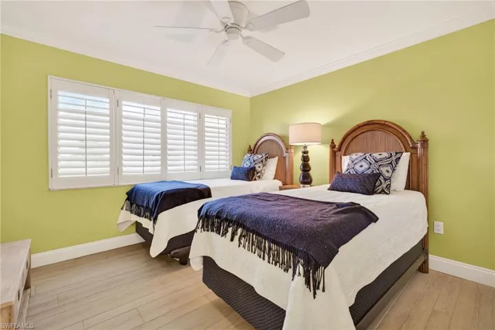 Bedroom with ornamental molding, light wood-type flooring, and ceiling fan