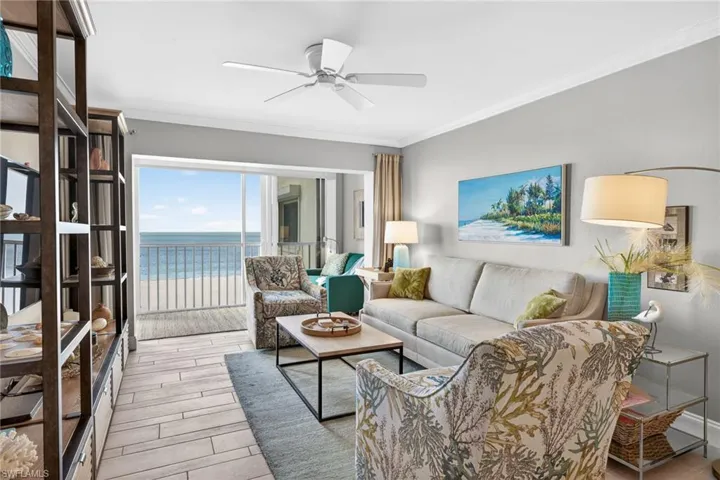 Living area with a water view, ornamental molding, wood finish floors, and ceiling fan