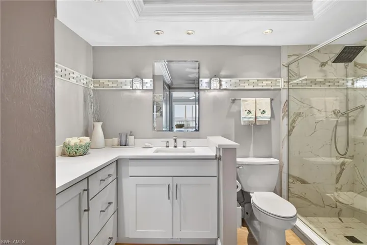 Full bath with crown molding, vanity, a marble finish shower, and recessed lighting