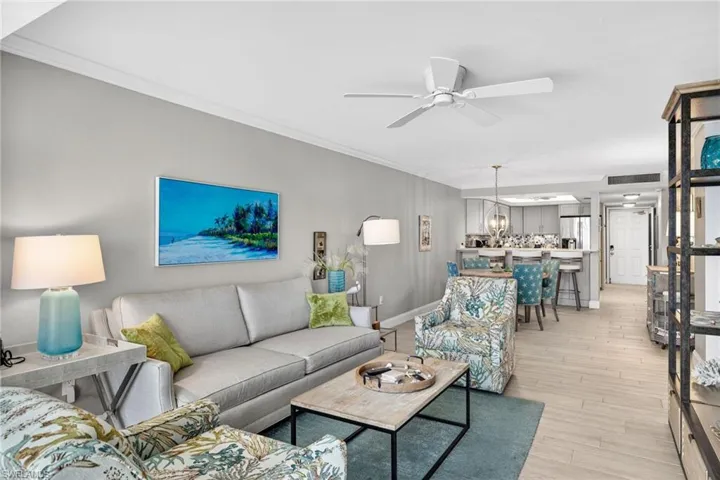 Living area featuring crown molding, light wood-style flooring, a ceiling fan, and a chandelier