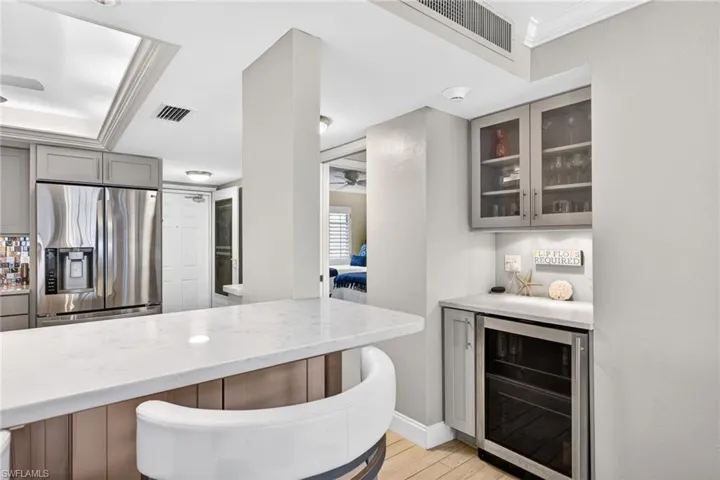Kitchen with gray cabinetry, stainless steel fridge, wine cooler, a ceiling fan, and crown molding