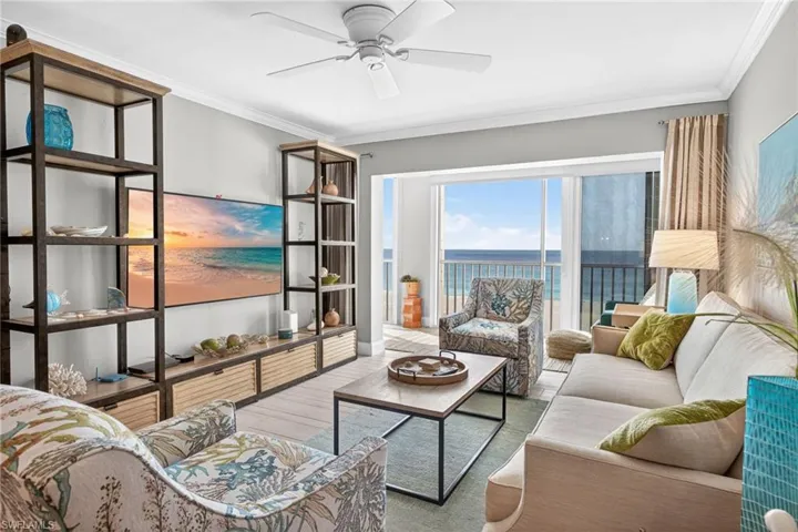 Living area featuring a water view, ornamental molding, wood finished floors, and a ceiling fan