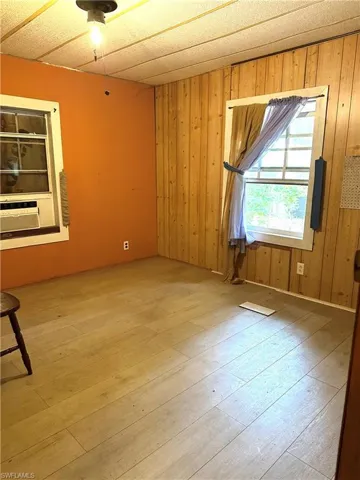 Empty room with wooden walls, cooling unit, and hardwood / wood-style floors