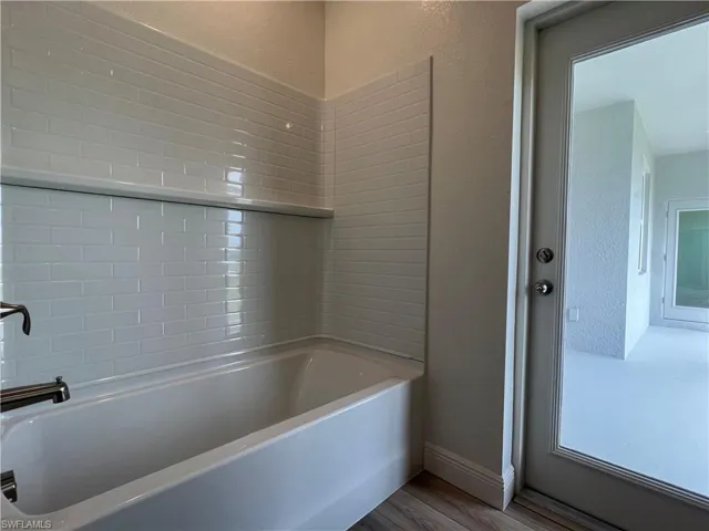 Bathroom featuring wood finished floors and tub / shower combination
