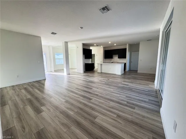 Unfurnished living room featuring wood finished floors, recessed lighting, baseboards, and a textured ceiling