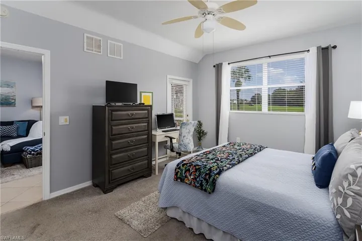 Bedroom with light carpet, ceiling fan, and lofted ceiling