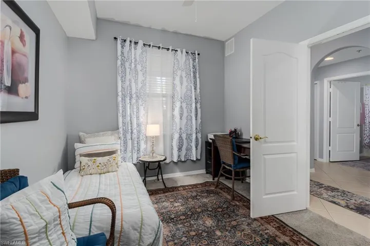 Tiled bedroom featuring arched walkways and an office area