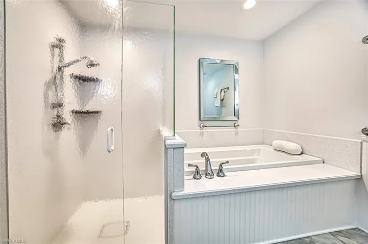 Bathroom with a stall shower, a garden tub, and recessed lighting