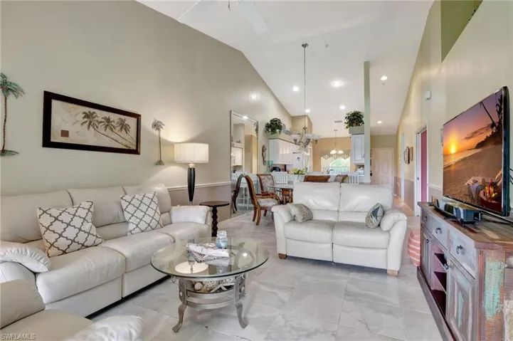 Tiled living room featuring ceiling fan and high vaulted ceiling