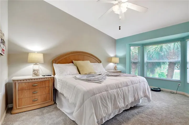 Bedroom with light colored carpet, lofted ceiling, and ceiling fan