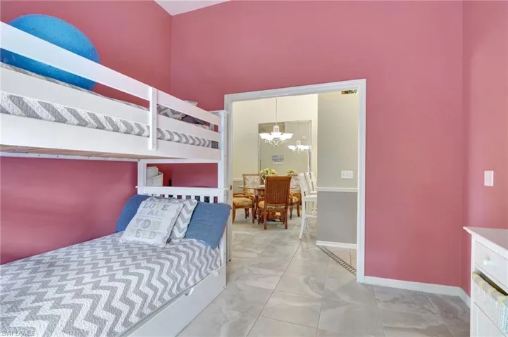 Bedroom with a high ceiling, light tile patterned floors, and an inviting chandelier