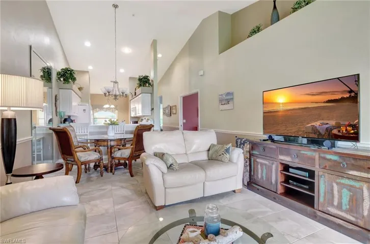 Tiled living room featuring high vaulted ceiling and a chandelier