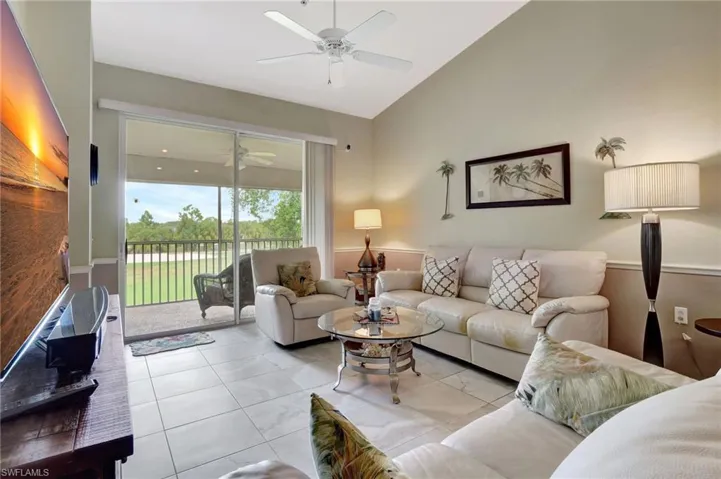 Tiled living room with ceiling fan and high vaulted ceiling