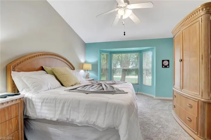 Carpeted bedroom with vaulted ceiling and ceiling fan