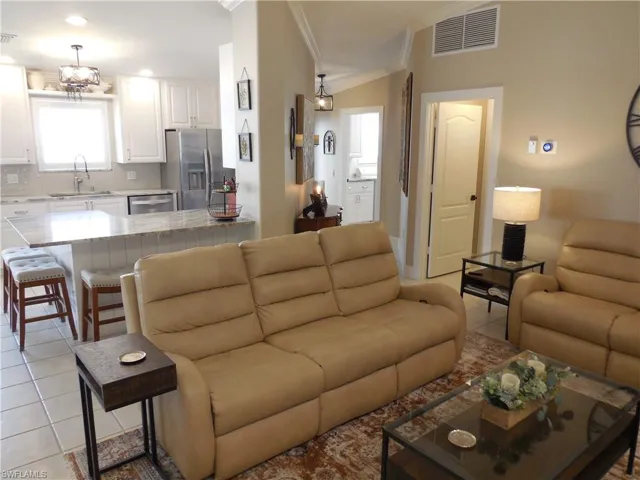 Living room with recessed lighting, ornamental molding, visible vents, and light tile patterned floors