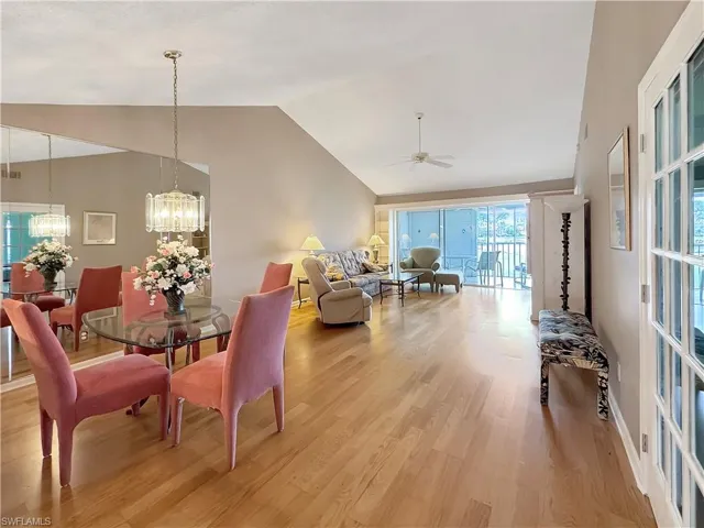 Dining room featuring lofted ceiling, light wood-type flooring, and ceiling fan with notable chandelier