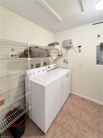 Laundry area featuring washer and dryer, a textured ceiling, and electric panel