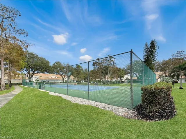 View of tennis court featuring a yard