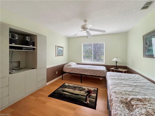 Bedroom featuring ceiling fan, a textured ceiling, and light wood-type flooring