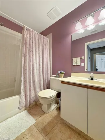 Full bathroom featuring toilet, vanity, tile patterned floors, and shower / tub combo with curtain