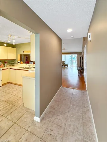 Corridor with a textured ceiling, light tile patterned flooring, and sink