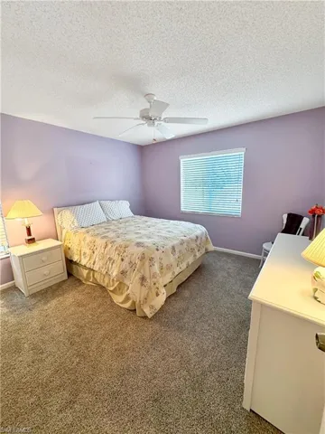 Carpeted bedroom with a textured ceiling and ceiling fan