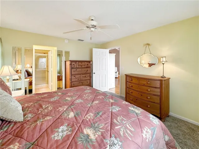 Bedroom featuring ceiling fan, ensuite bathroom, and carpet floors