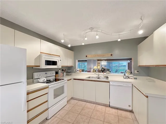 Kitchen with sink, white appliances, white cabinetry, a textured ceiling, and light tile patterned floors