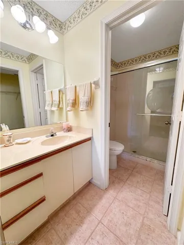 Bathroom with tile patterned floors, toilet, a shower with door, and vanity