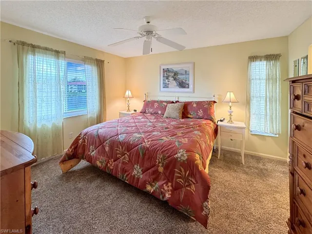 Bedroom featuring ceiling fan, carpet, and a textured ceiling