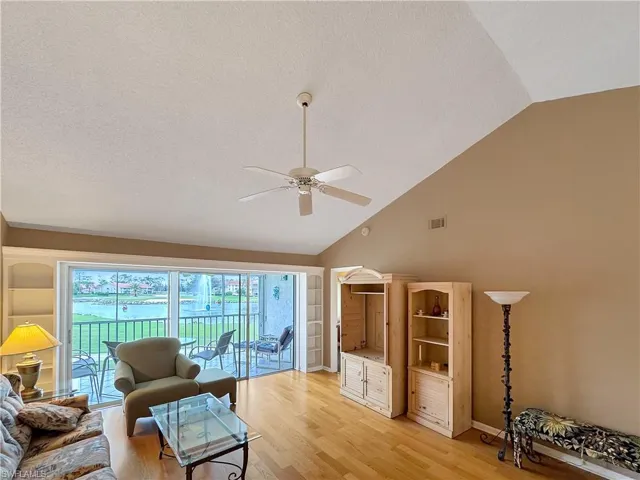 Living room with lofted ceiling, light wood-type flooring, built in features, and ceiling fan