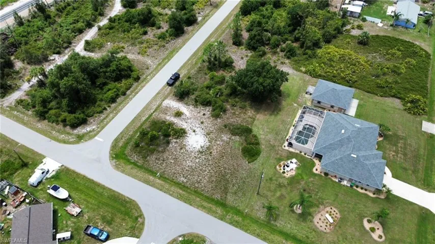 Aerial perspective showcasing a corner lot with undeveloped land