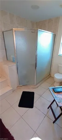 Full bathroom featuring a stall shower and light tile patterned flooring