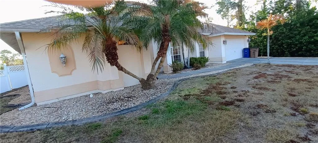 View of side of home with a shingled roof, an attached garage, stucco siding, and concrete driveway