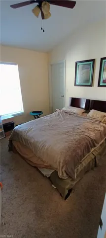 Bedroom featuring carpet, ceiling fan, and vaulted ceiling