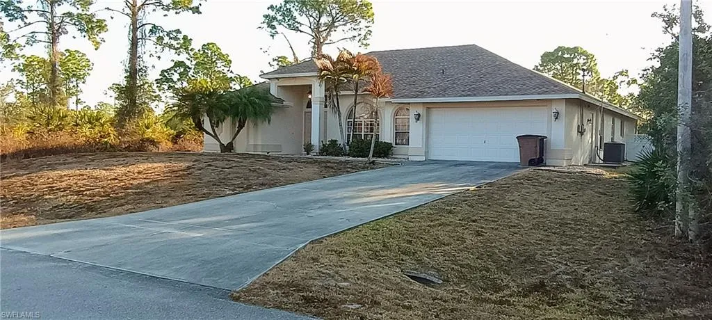 View of front of property featuring driveway, an attached garage, a shingled roof, and stucco siding