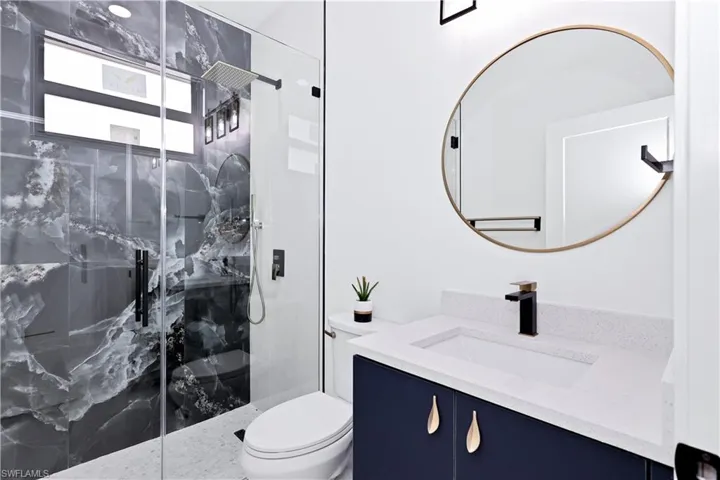 Bathroom with toilet, vanity, and a tile shower