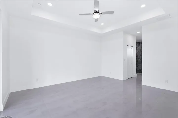 Empty room featuring ceiling fan and a raised ceiling