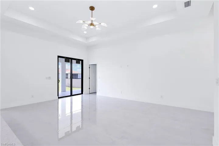 Spare room with a high ceiling, a tray ceiling, and an inviting chandelier