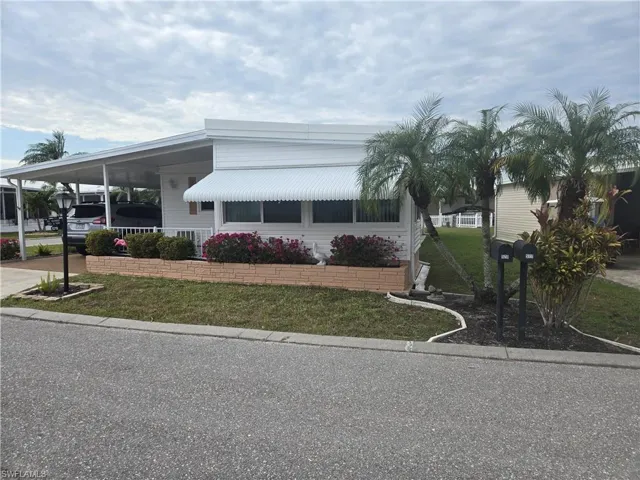 View of front of home with a carport and a front lawn