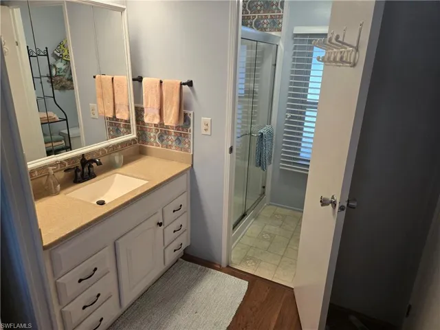Bathroom featuring hardwood / wood-style flooring, vanity, and an enclosed shower