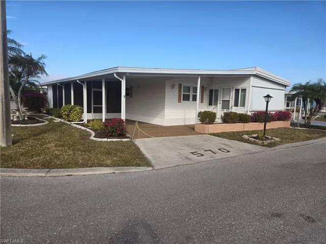View of front facade featuring a front yard and a carport