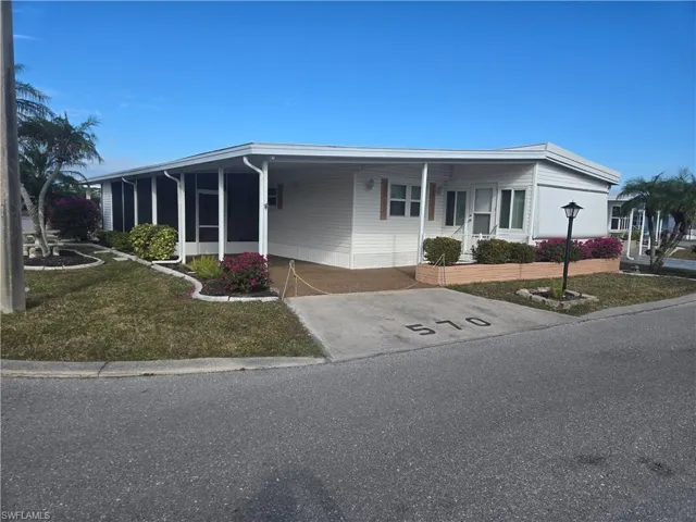 View of front of property with a carport and a front yard