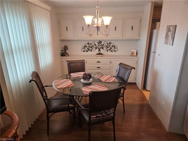 Dining area with dark wood-type flooring and an inviting chandelier