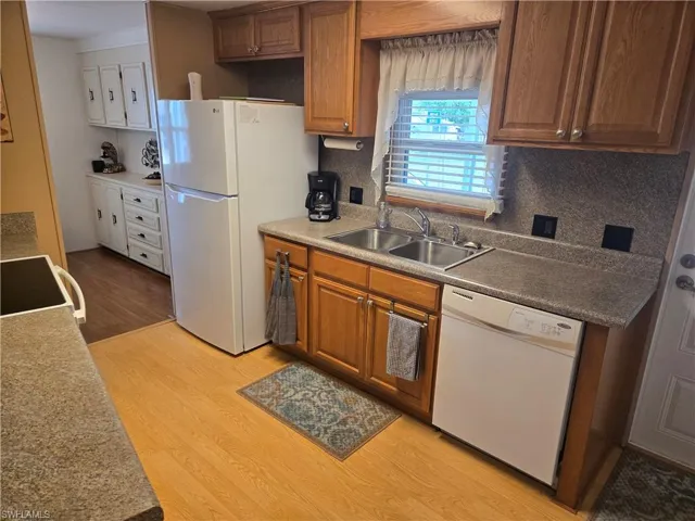 Kitchen featuring decorative backsplash, sink, white appliances, and light hardwood / wood-style flooring