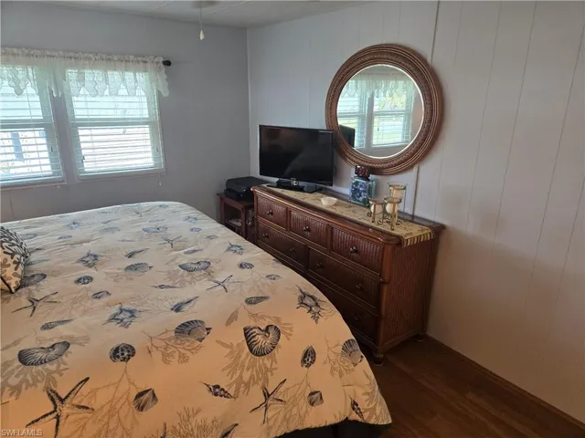 Bedroom with dark wood-type flooring and wood walls