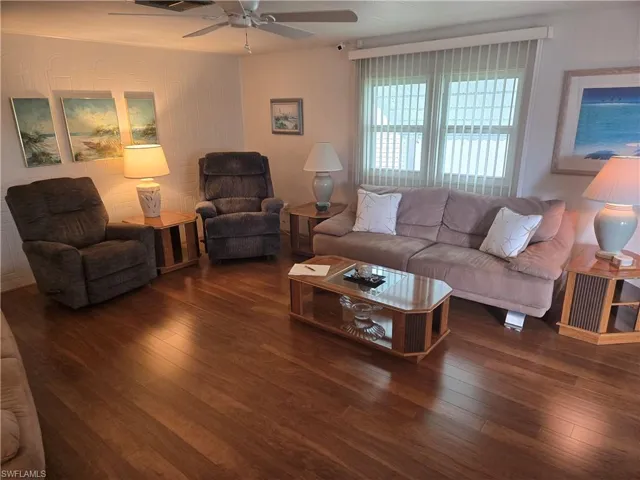 Living room featuring ceiling fan and dark wood-type flooring
