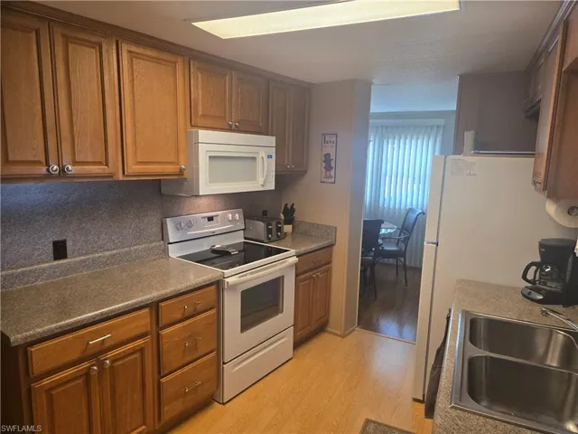 Kitchen with sink, white appliances, and light hardwood / wood-style flooring